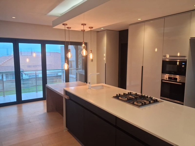 Modern kitchen featuring a central island with gas cooktop, integrated cabinetry, built-in appliances, and large sliding doors leading to an outdoor area.