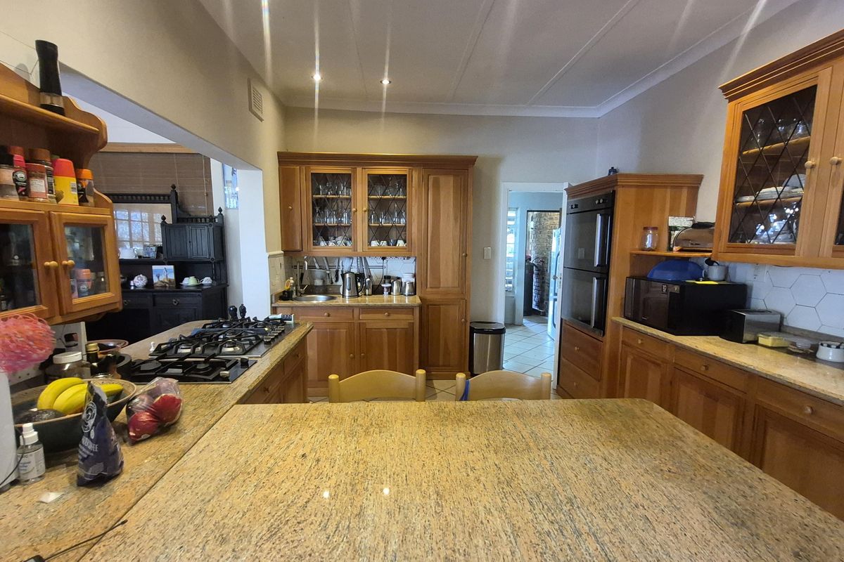 A traditional kitchen featuring extensive wooden cabinetry, granite countertops, a built-in double oven, and a gas hob, offering a warm and functional workspace.