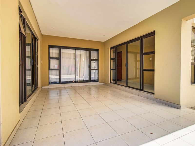 A spacious, covered patio area featuring neutral tiled flooring and large sliding glass doors providing seamless access to the interior living spaces.