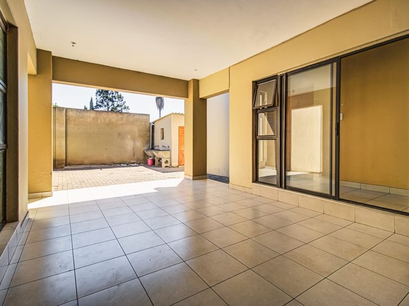 A spacious covered patio featuring tiled flooring and direct access to the rear yard, providing a versatile outdoor living area.