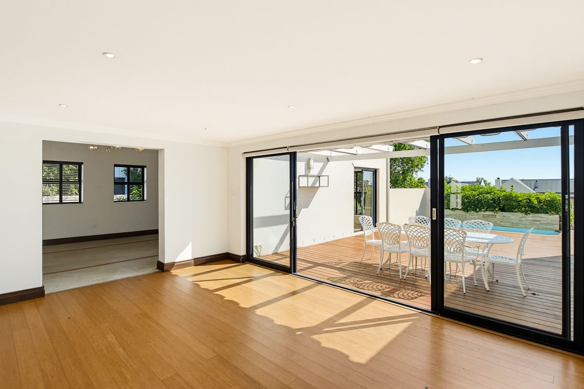 Spacious living area featuring timber flooring, recessed downlights, and large sliding glass doors that open onto an outdoor deck.