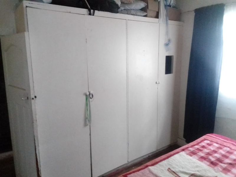 A bedroom featuring a large, white built-in wardrobe with multiple doors, providing ample storage space.