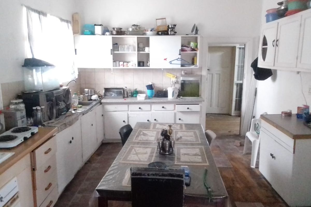 A functional kitchen space featuring built-in cabinetry, laminate countertops, and a tiled backsplash, offering potential for modernization and renovation.
