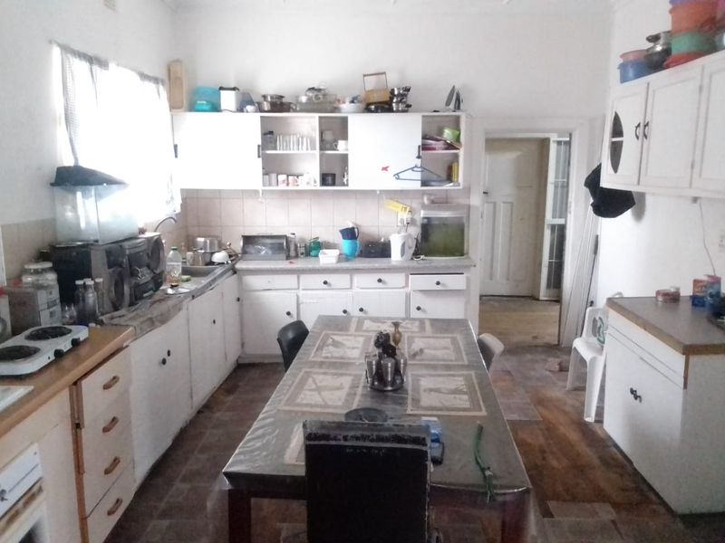 A functional kitchen space featuring built-in cabinetry, laminate countertops, and a tiled backsplash, offering potential for modernization and renovation.