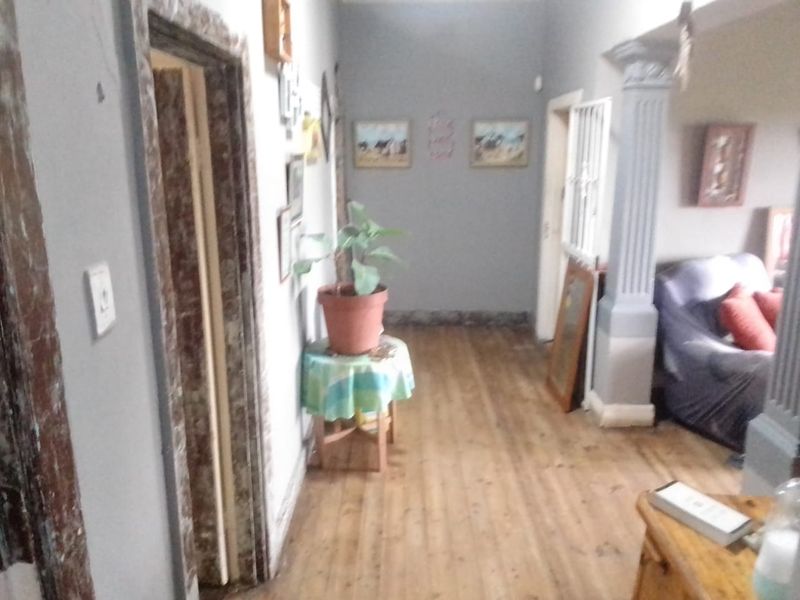 A hallway featuring hardwood flooring and a decorative column, connecting to adjacent living spaces.