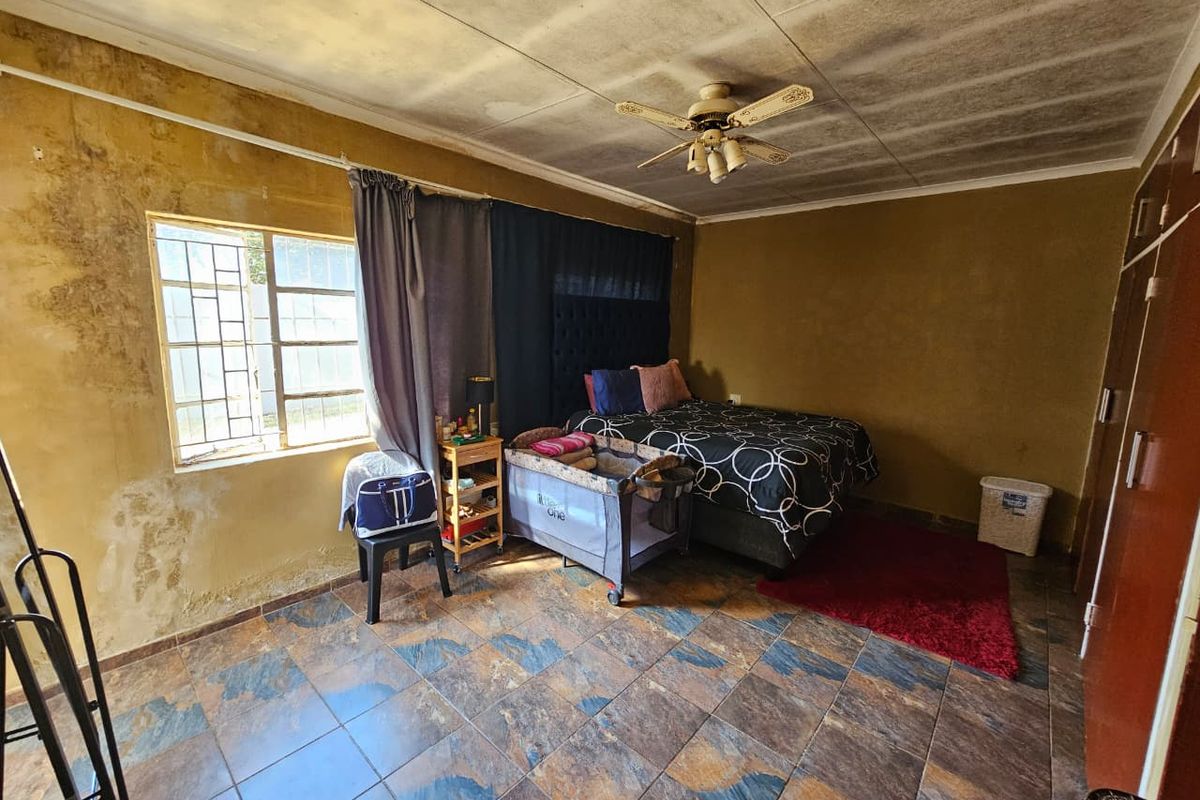 Bedroom featuring tiled flooring, a ceiling fan, and built-in wardrobe. The room requires significant cosmetic attention due to visible wall and ceiling damage.