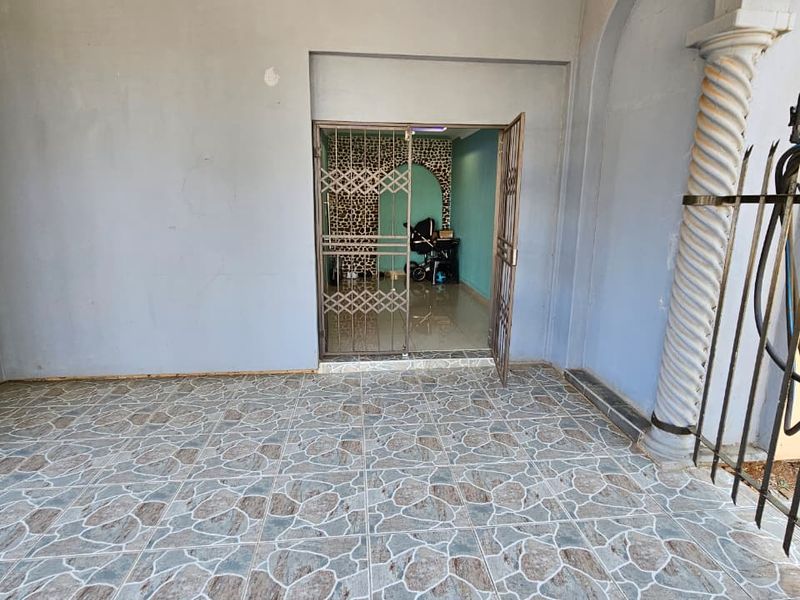 Covered patio area featuring decorative column, tiled flooring, and a secure metal entrance gate leading into the home.