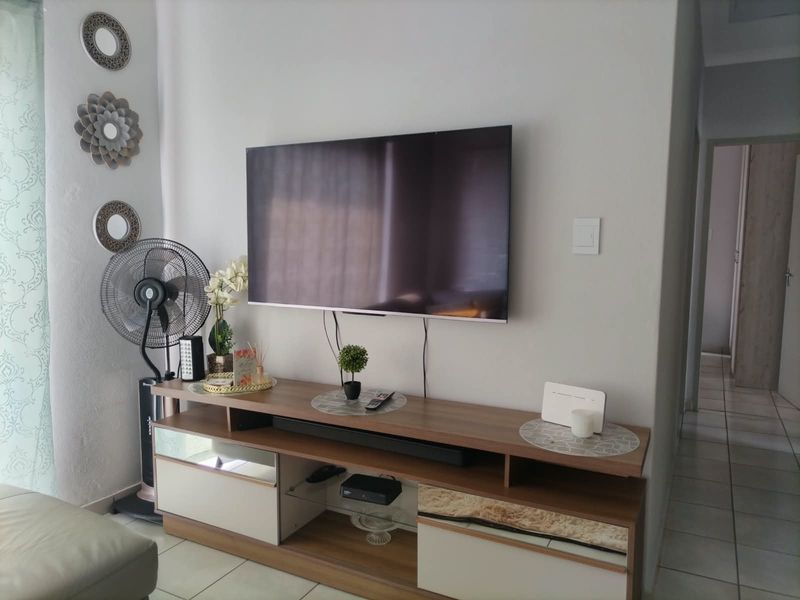A living room area featuring tiled flooring and a wall-mounted television setup with neutral wall finishes.
