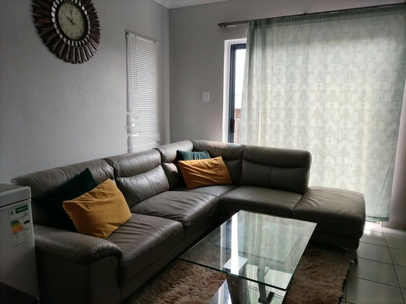 A comfortable living room featuring tiled flooring and a sliding glass door that provides natural light and access to the exterior.