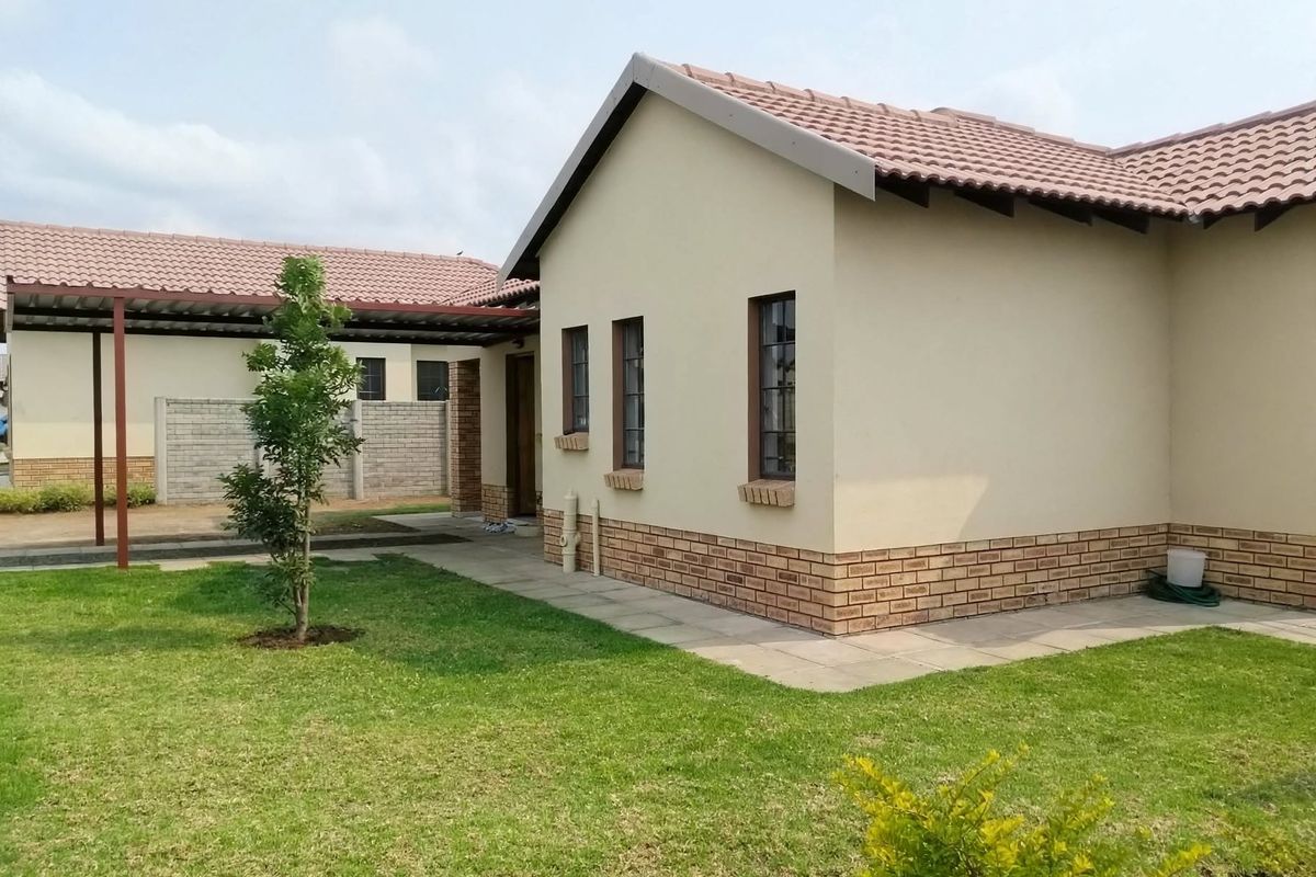 A view of the rear exterior of the house featuring a tiled roof, brick accents, a paved walkway, and an attached carport.
