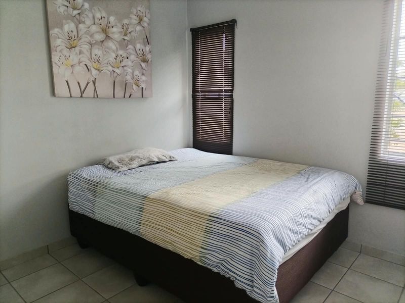 A bedroom featuring tiled flooring and dark venetian blinds, providing a neutral base for interior design updates.