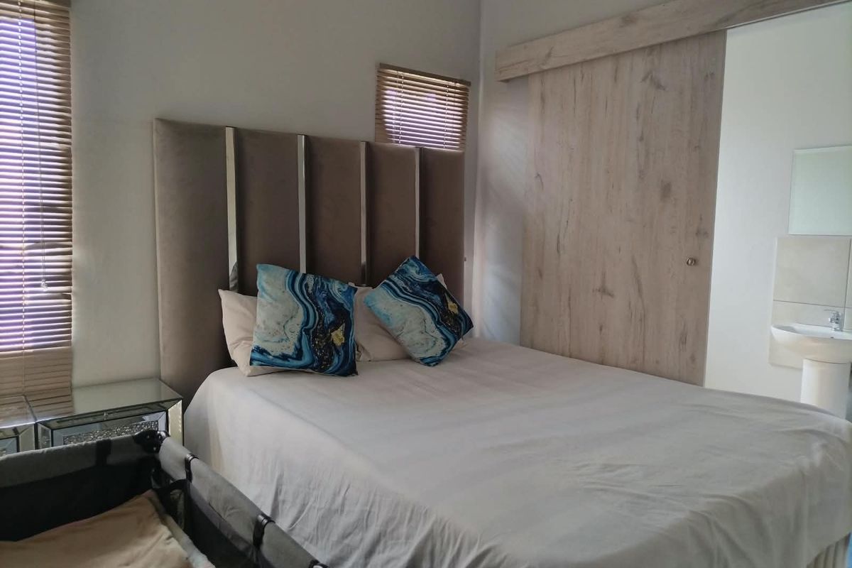 A well-maintained bedroom featuring a sliding barn door, venetian blinds, and an integrated pedestal basin.