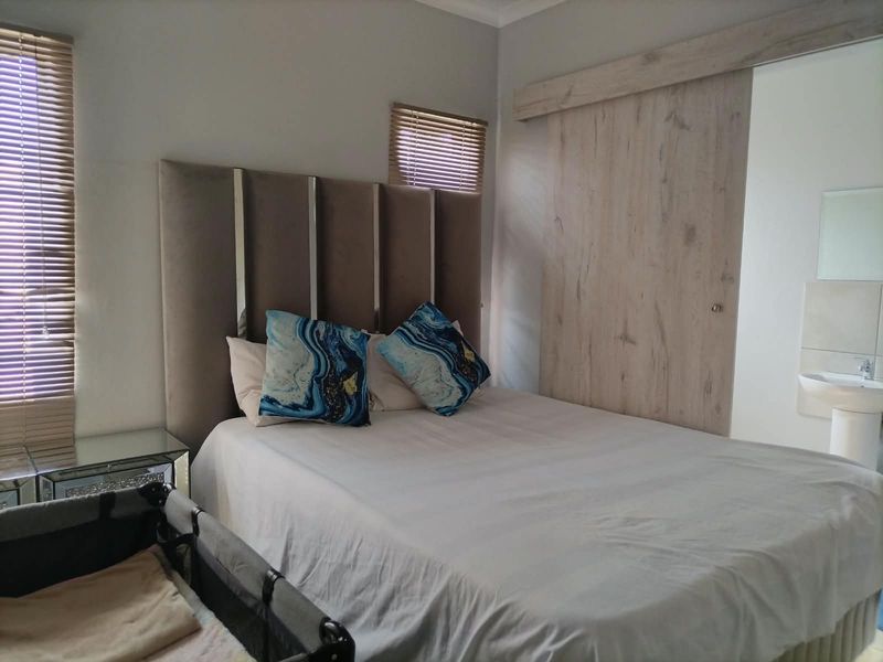 A well-maintained bedroom featuring a sliding barn door, venetian blinds, and an integrated pedestal basin.