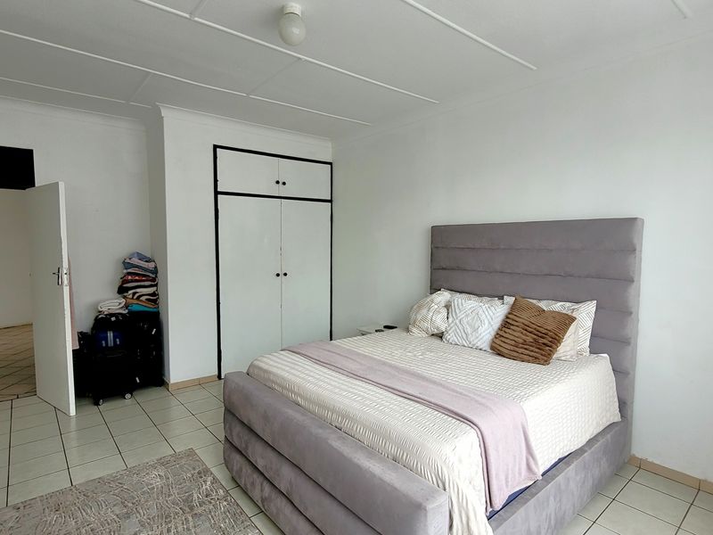 A bedroom featuring tiled flooring and a built-in wardrobe, offering a functional space with neutral finishes.