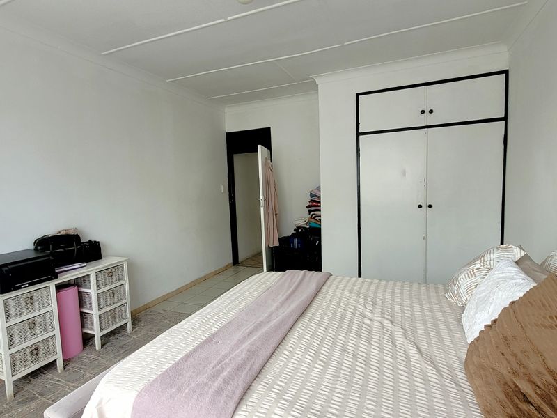 A bedroom featuring tiled flooring, a built-in wardrobe with white doors, and a coved ceiling.