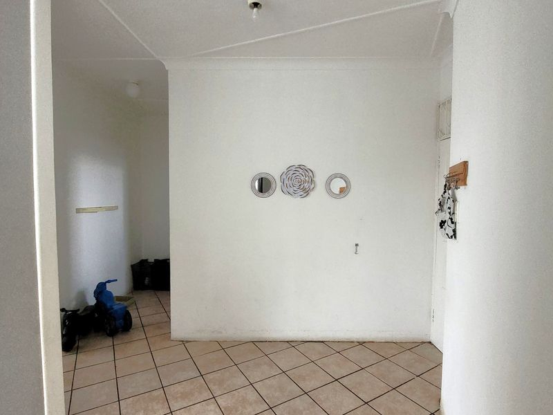 A simple entry area featuring tiled flooring and plain white walls, providing a blank canvas for potential interior design updates.