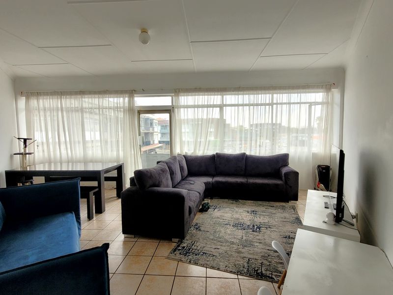 Spacious living area featuring tiled flooring and a large window expanse that provides ample natural light.
