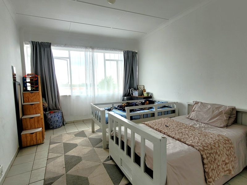 A functional bedroom featuring tiled flooring and a large window that allows for natural light.