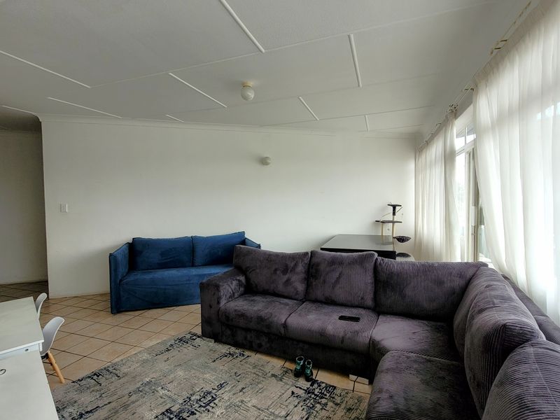 A spacious living room featuring tiled flooring and large windows that allow for ample natural light.