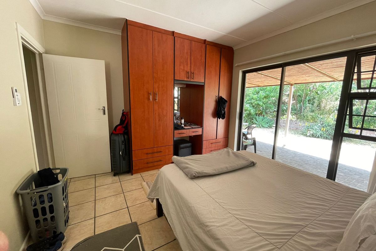 Bedroom featuring built-in wooden cupboards, tiled flooring, and a large sliding glass door providing direct access to the outdoor patio area.