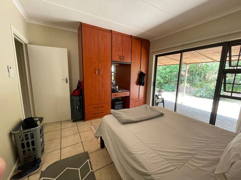 Bedroom featuring built-in wooden cupboards, tiled flooring, and a large sliding glass door providing direct access to the outdoor patio area.