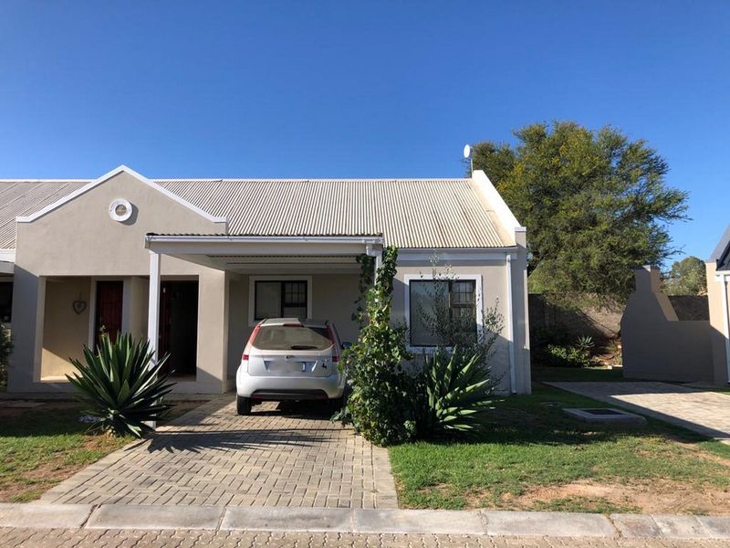 Front elevation of a townhouse featuring a paved driveway, integrated carport, and low-maintenance exterior finishes.