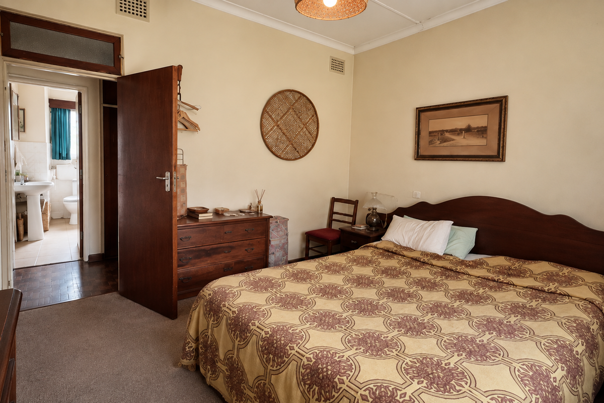 A well-proportioned bedroom featuring built-in cupboards, neutral wall finishes, and carpeted flooring, with direct access to an adjoining bathroom.