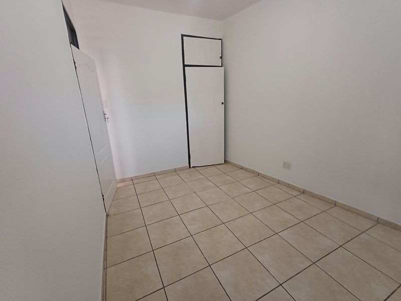 A clean, empty bedroom featuring neutral tiled flooring and a built-in cupboard, providing a versatile blank canvas for personalization.