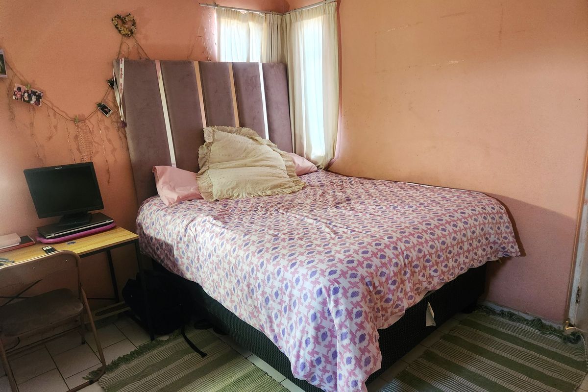 A bedroom featuring tiled flooring and corner windows, currently requiring cosmetic updates to the wall finishes.