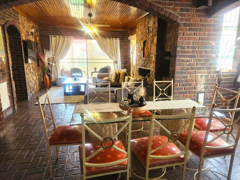 Open plan living and dining area featuring rustic exposed brick walls, stone fireplace, and timber ceiling, creating a warm and character-filled interior space.