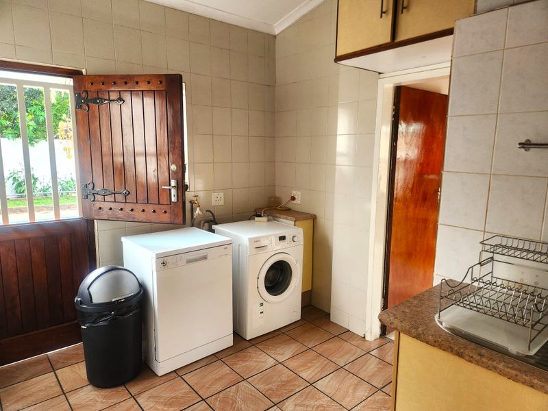 Functional laundry area featuring tiled walls, tiled flooring, built-in cabinetry, and dedicated plumbing connections for laundry appliances.