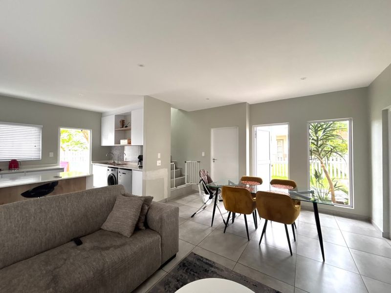 Open-plan living and dining area featuring tiled floors, recessed lighting, and a compact kitchen with built-in cabinetry and sink.