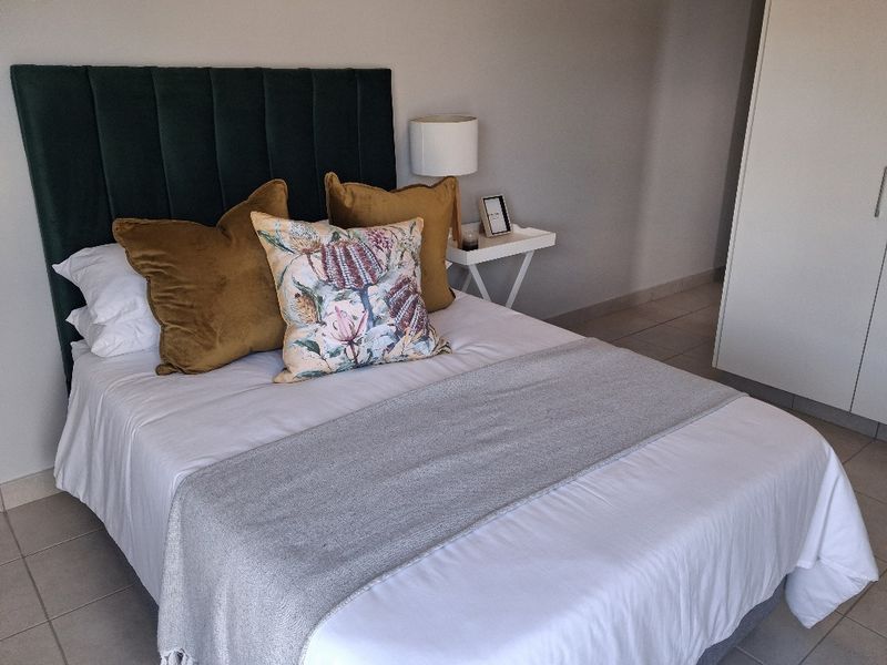 A well-maintained bedroom featuring neutral tiled flooring and a built-in wardrobe, providing a clean and functional living space.