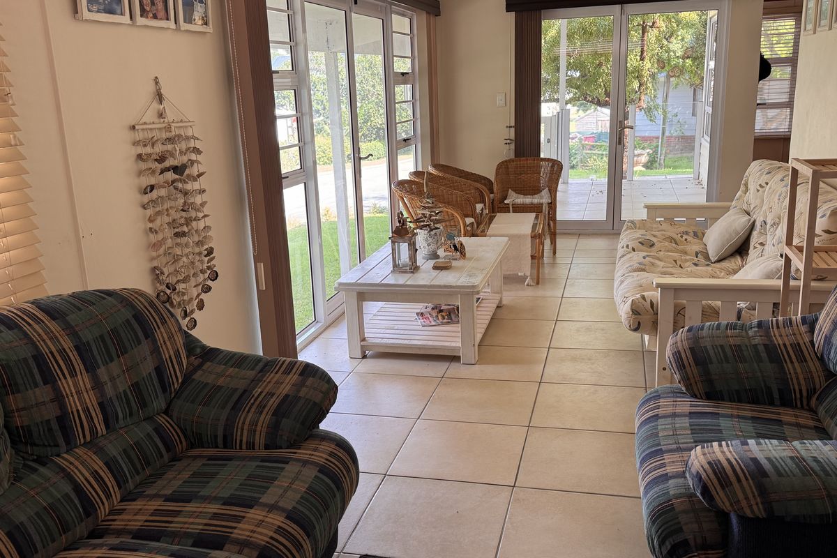 A bright living room featuring tiled flooring and large aluminium sliding doors that provide ample natural light and access to the outdoor area.