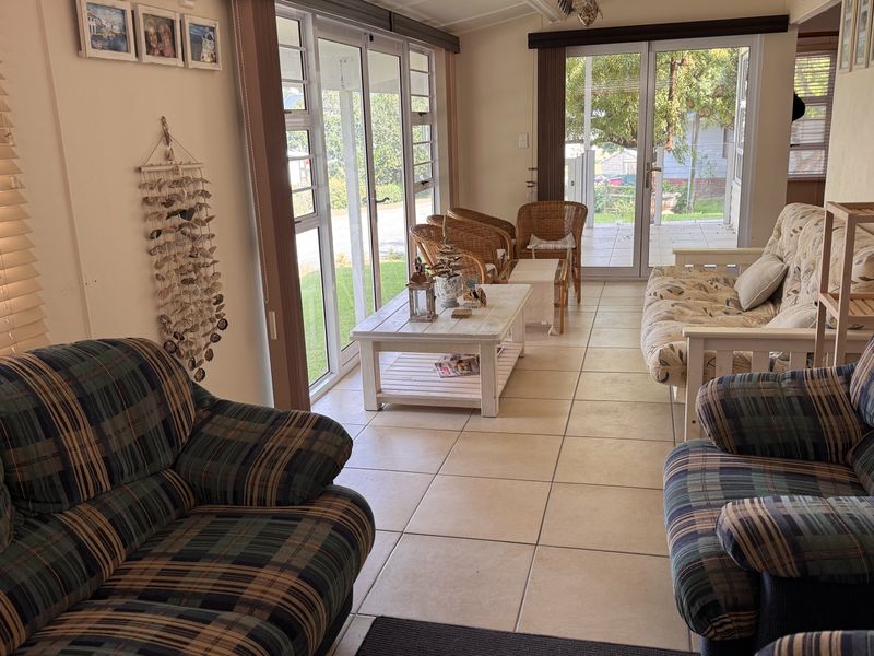 A bright living room featuring tiled flooring and large aluminium sliding doors that provide ample natural light and access to the outdoor area.