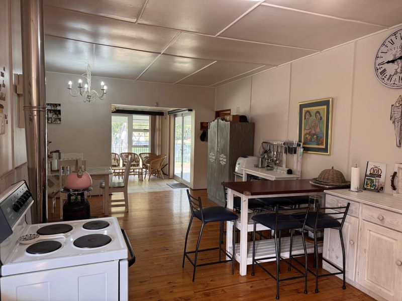 Open-plan living and kitchen area featuring timber flooring, an electric stove, and direct access to a tiled patio through sliding glass doors.