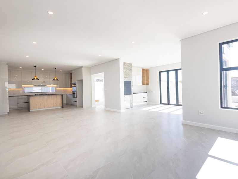 Spacious open-plan living and kitchen area featuring modern cabinetry, a central island, stone accents, and large sliding doors leading to the exterior.