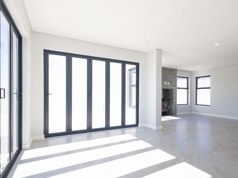 Spacious, light-filled living area featuring modern tiled floors, a striking stone-clad fireplace, and expansive stacking glass doors opening to the exterior.