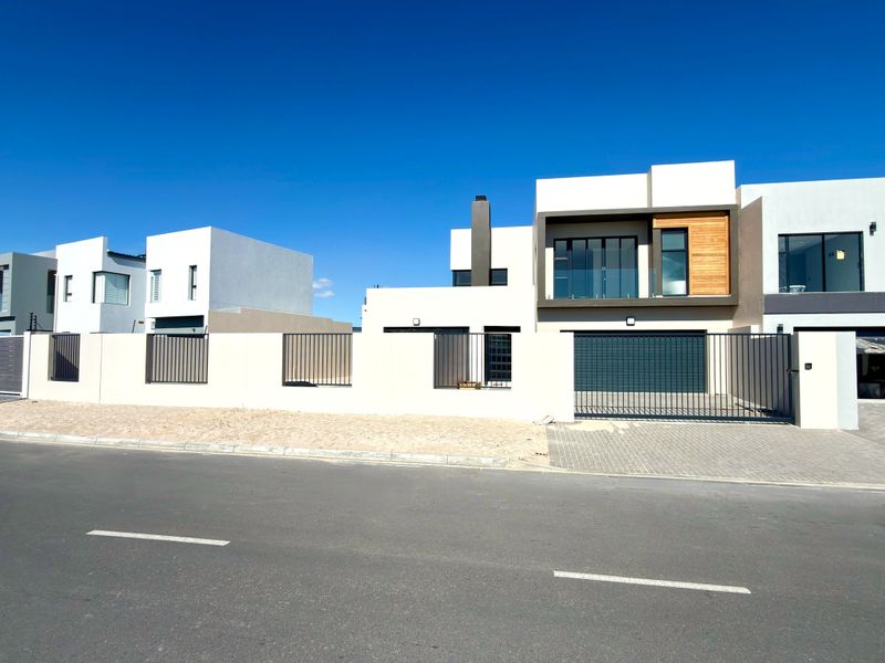Modern double-storey residential property featuring a contemporary facade, automated garage, and balcony with glass balustrades, situated in a clean suburban street setting.