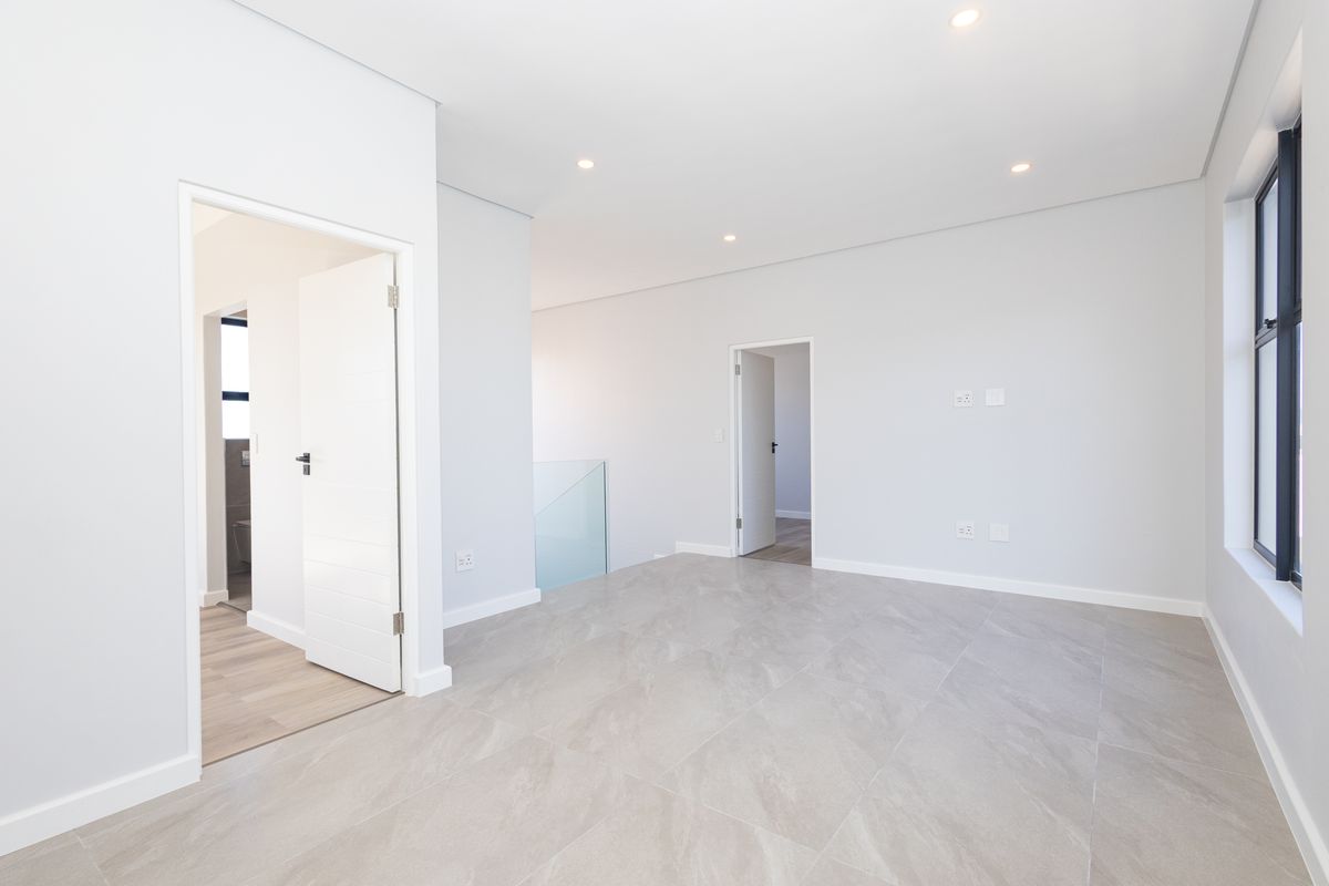 A bright, modern, and spacious bedroom featuring neutral tiled flooring, recessed downlighting, and clean finishes, ready for personalization.
