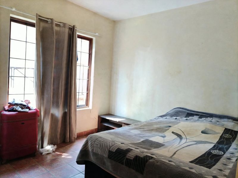 A bedroom featuring tiled flooring and timber-framed windows, requiring cosmetic updates to the wall finishes to improve the overall aesthetic.
