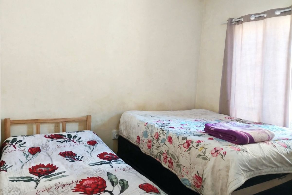 A bedroom featuring neutral walls with visible staining and a window fitted with a curtain rail.
