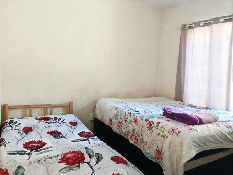 A bedroom featuring neutral walls with visible staining and a window fitted with a curtain rail.