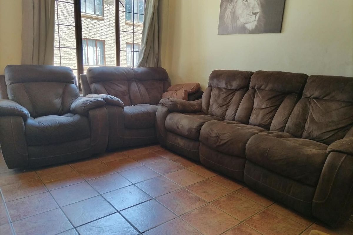 A living room area featuring tiled flooring and a large window providing natural light.