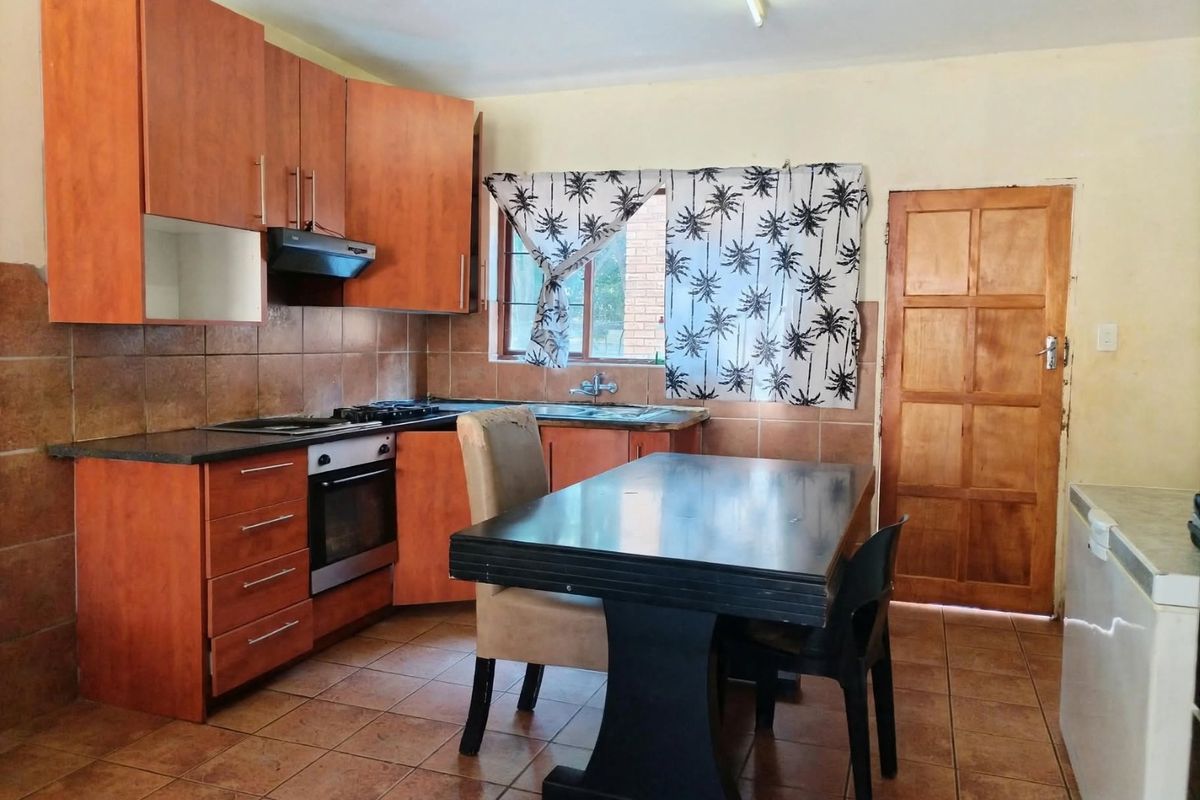 A functional kitchen featuring wooden cabinetry, built-in oven and hob, tiled backsplash, and direct access to an exterior door.