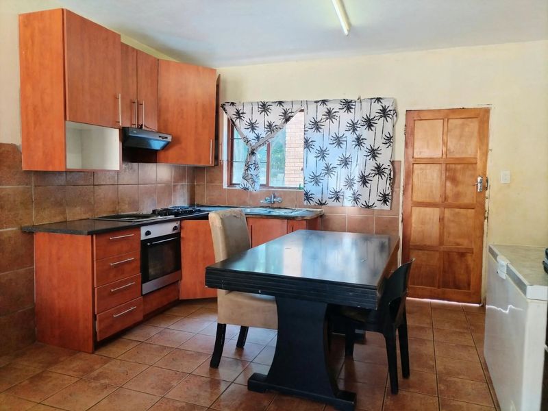 A functional kitchen featuring wooden cabinetry, built-in oven and hob, tiled backsplash, and direct access to an exterior door.
