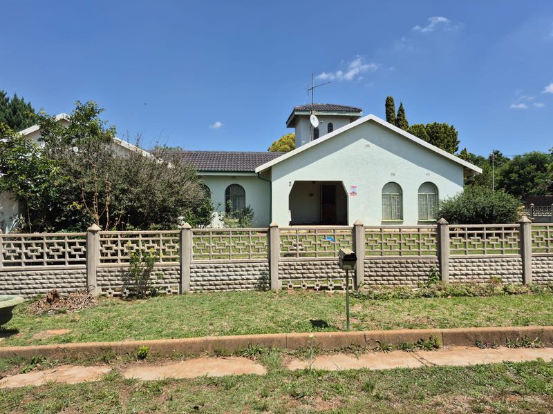 Front view of a single-story house featuring a tiled roof, arched windows, a covered entrance, and a precast concrete boundary wall.