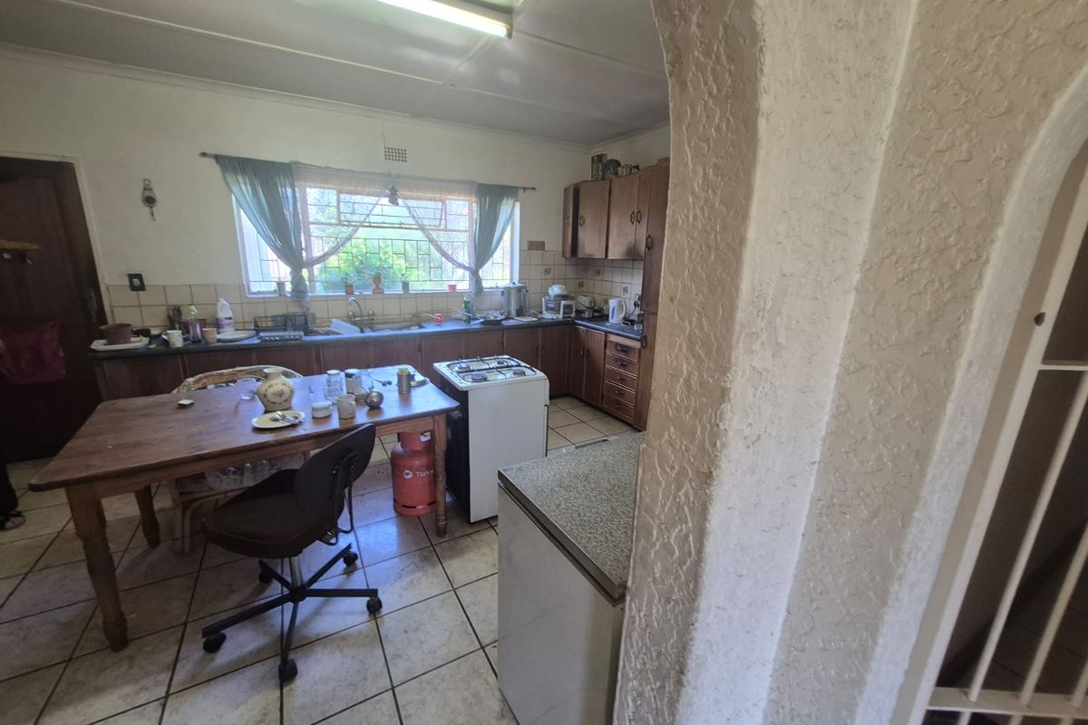 A dated kitchen featuring wooden cabinetry, tiled flooring, and a double sink, offering significant potential for modernization and renovation.