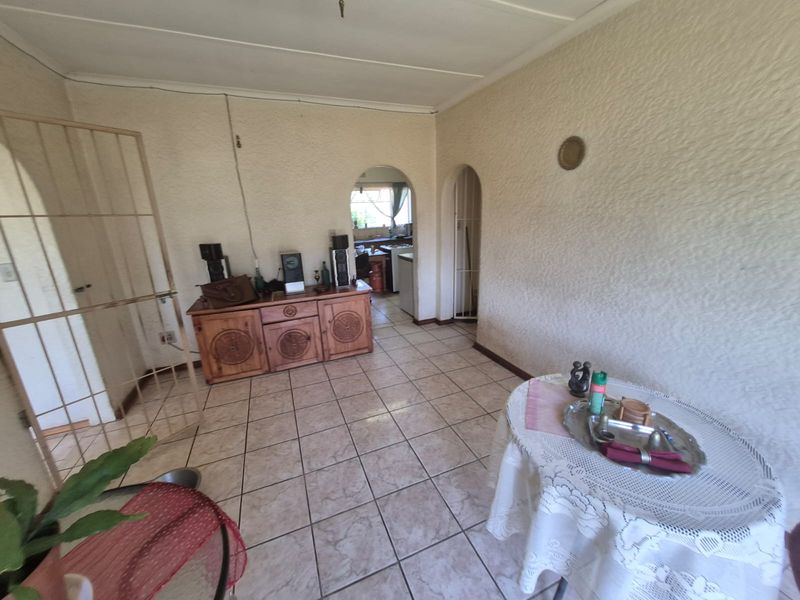 Living area featuring tiled flooring and arched doorways leading to adjacent rooms, with textured wall finishes throughout.