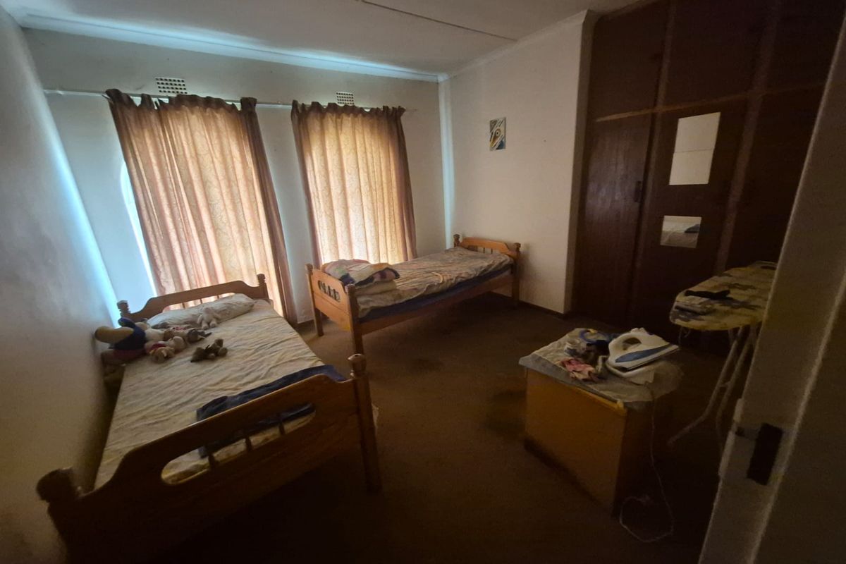 A bedroom featuring built-in wooden cupboards and carpeted flooring, offering a functional space with potential for modernization.